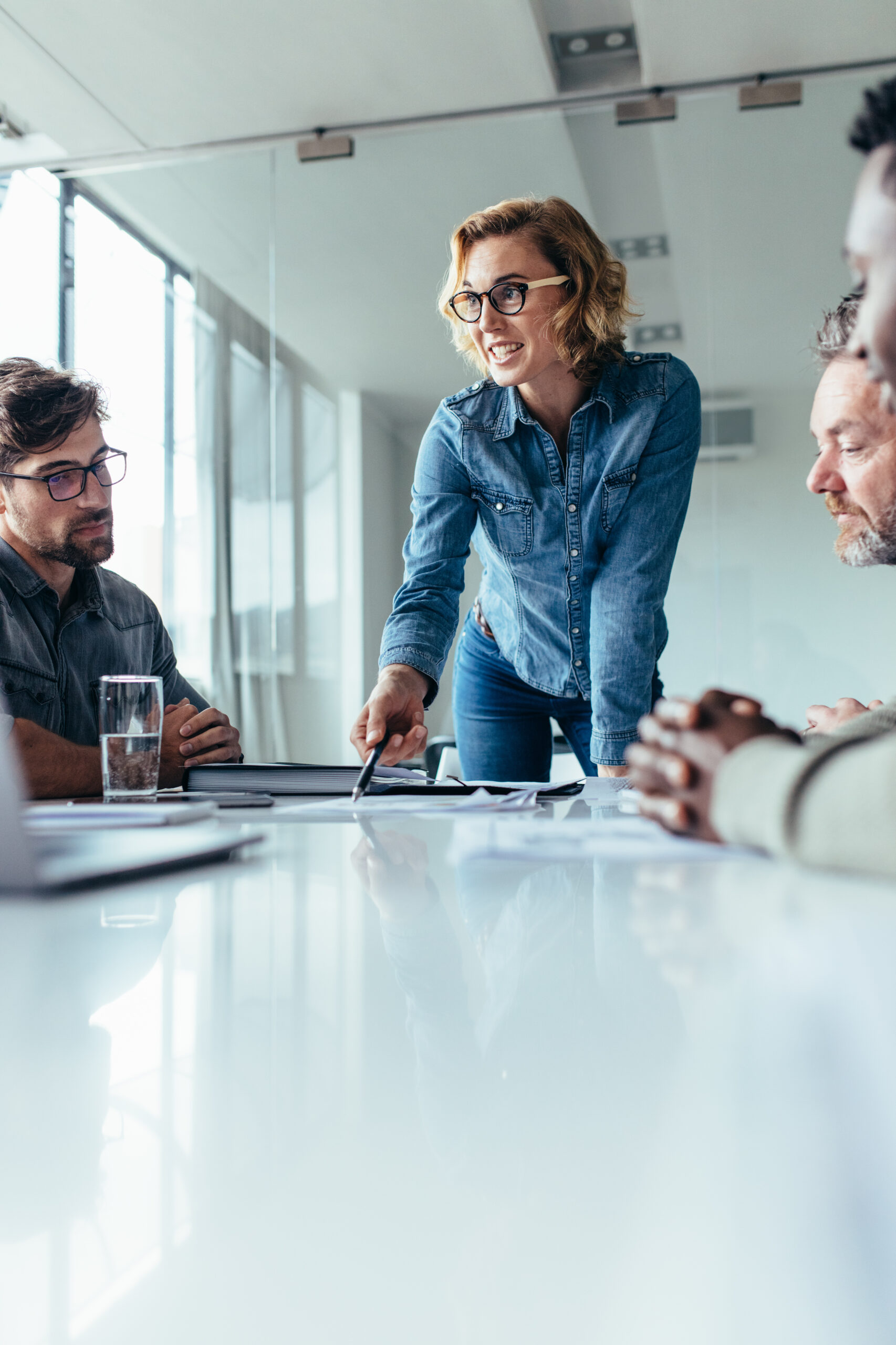 Businesswoman explaining to coworkers about project in office. Beautiful woman explaining her ideas to colleagues in conference room.